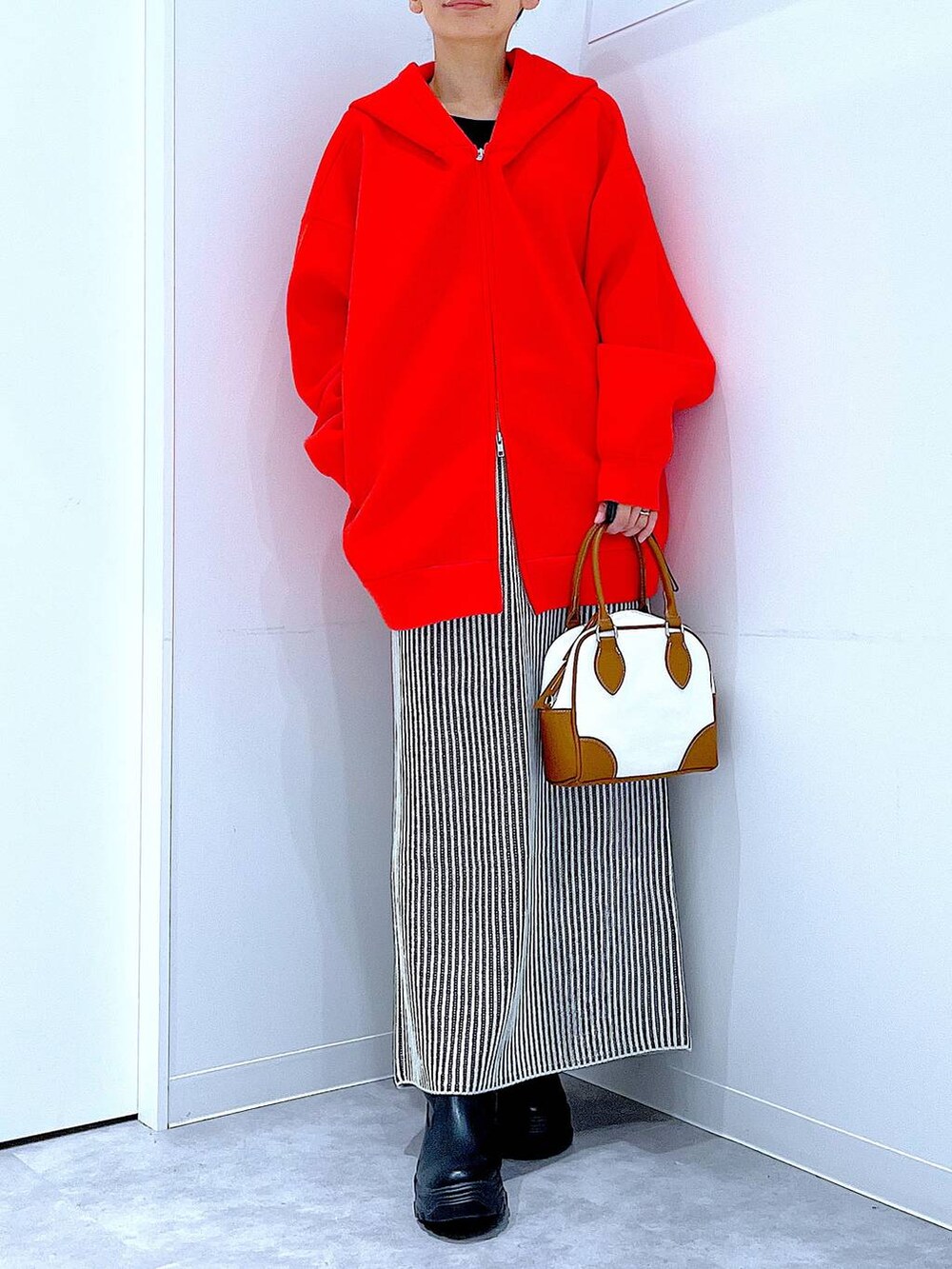 ブラック系のブーツ、ベージュ系のスカート、ホワイト系のハンドバッグを着用したレディースの秋コーディネートの6枚目の写真