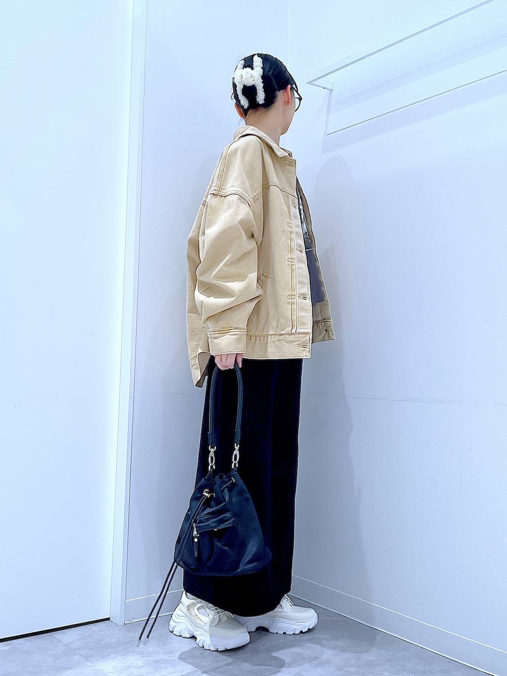 ブラック系のスカート、ベージュ系のデニムジャケット、ブラック系のショルダーバッグを着用したレディースの春コーディネートの4枚目の写真