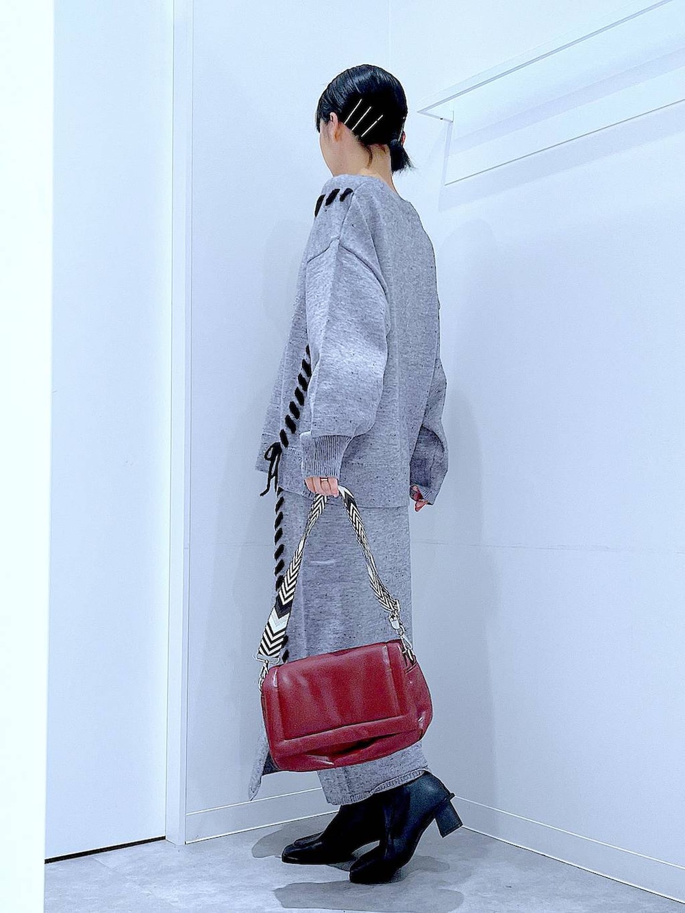 グレー系のニット/セーター、レッド系のショルダーバッグ、グレー系のスカートを着用したレディースの冬コーディネートの3枚目の写真