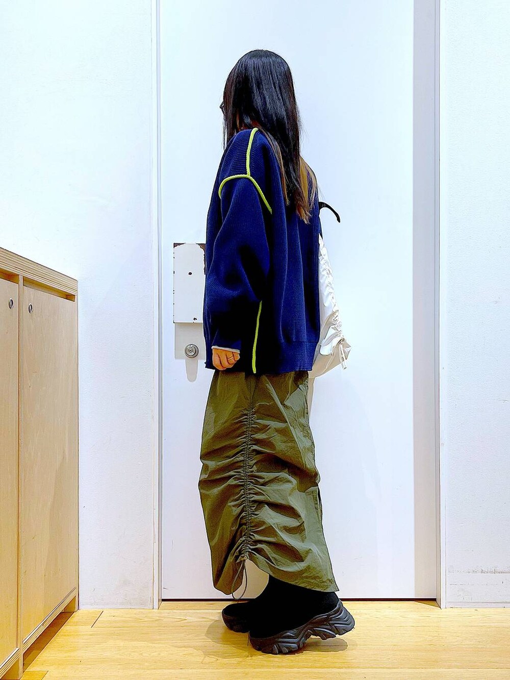 グレー系のスウェット、ブラック系のブーツ、グリーン系のスカートを着用したレディースの冬コーディネートの3枚目の写真