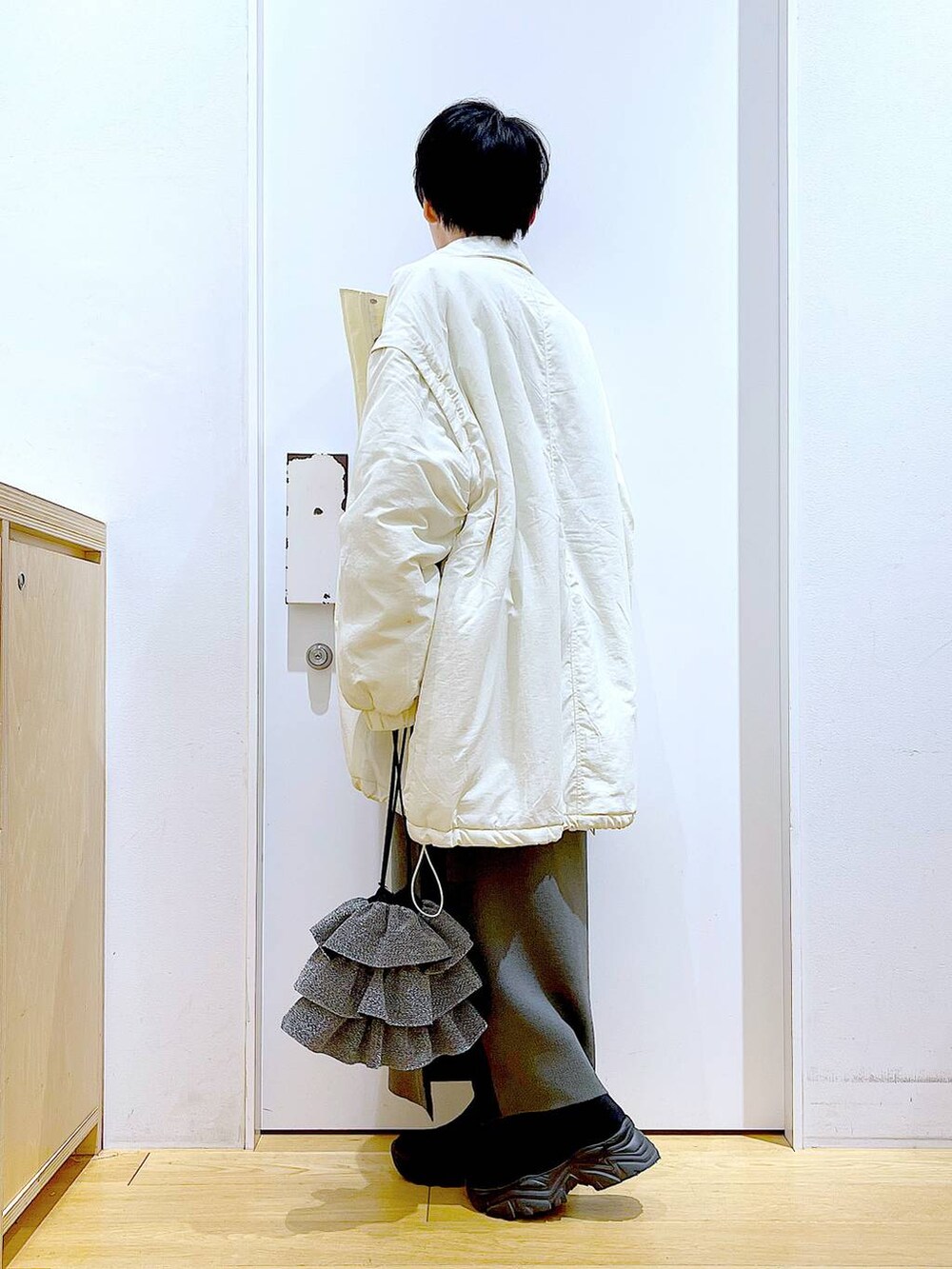 グレー系のスカート、ブラック系のブーツ、ホワイト系のその他アウターを着用したレディースの冬コーディネートの3枚目の写真