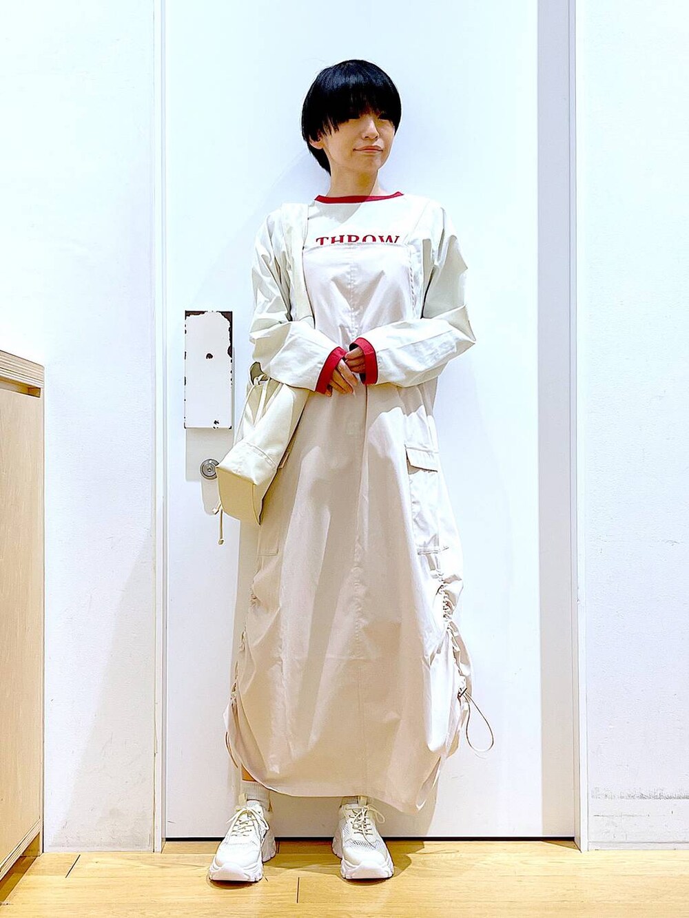 ホワイト系のスニーカー、ベージュ系のジャンパースカート、ベージュ系のTシャツ/カットソーを着用したレディースの春コーディネートの2枚目の写真