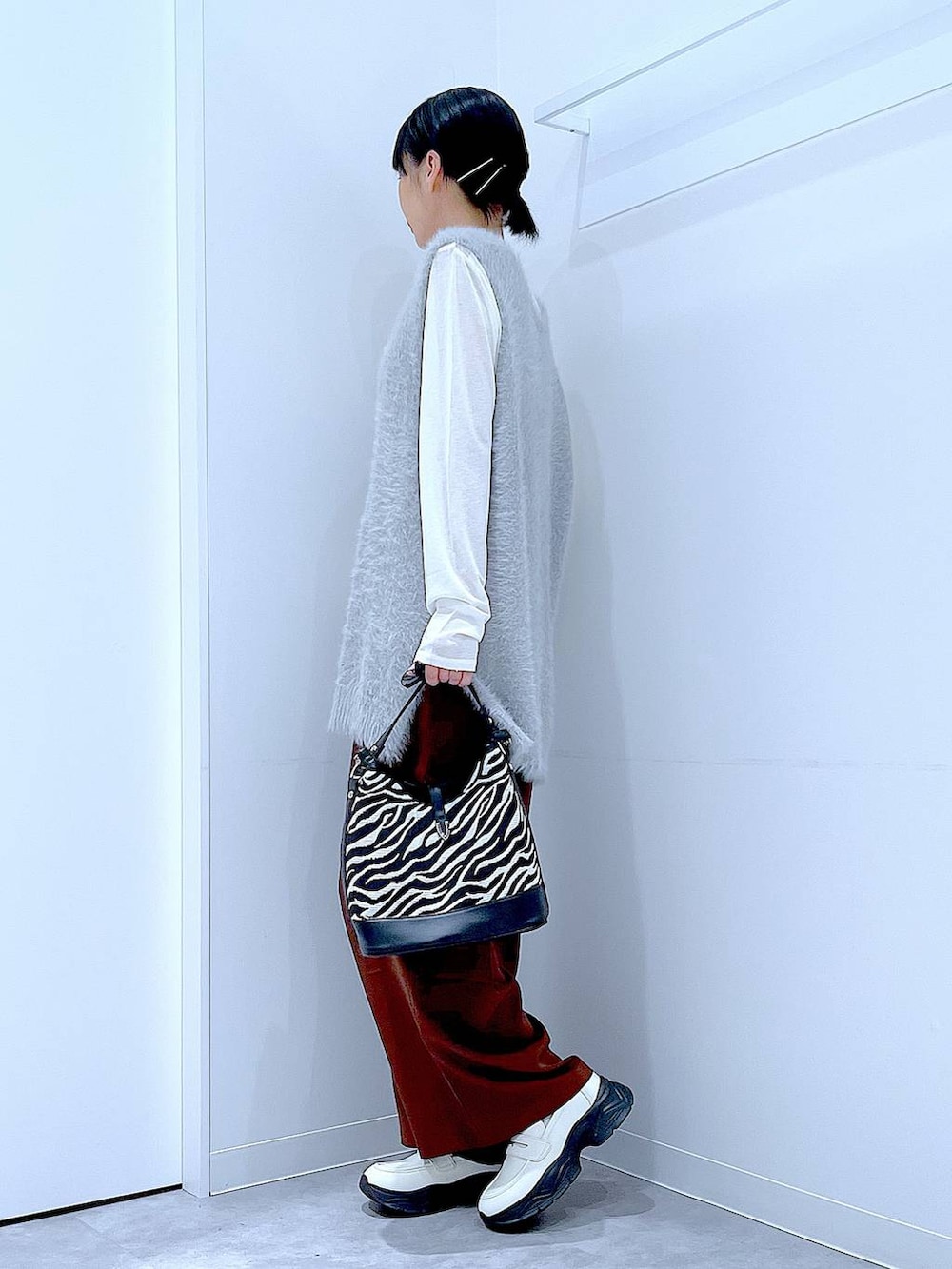 ホワイト系のTシャツ/カットソー、ホワイト系のローファー、グレー系のベストを着用したレディースの秋コーディネートの3枚目の写真