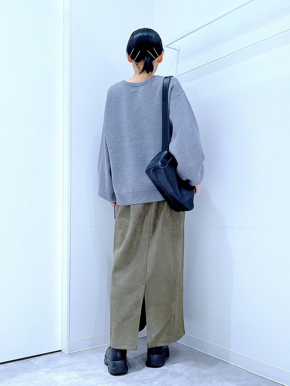 ブラック系のショルダーバッグ、ブラック系のブーツ、グリーン系のスカートを着用したレディースの冬コーディネートの5枚目の写真