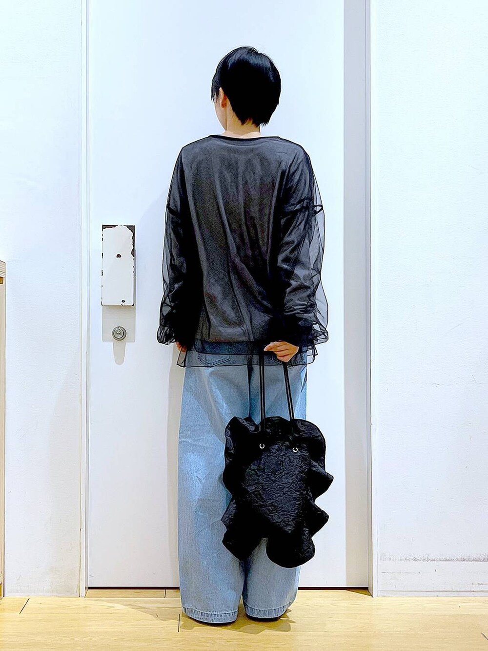 ブラック系のスニーカー、ブラック系のショルダーバッグ、ブルー系のデニムパンツを着用したレディースの春コーディネートの5枚目の写真