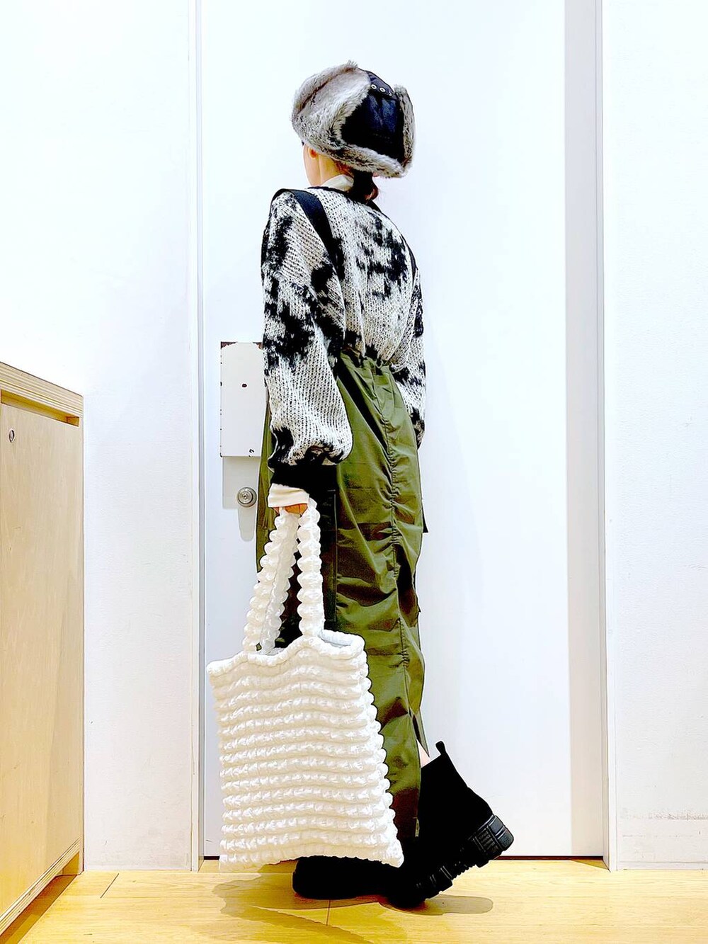 ホワイト系のトートバッグ、ベージュ系のTシャツ/カットソー、グリーン系のジャンパースカートを着用したレディースの冬コーディネートの3枚目の写真