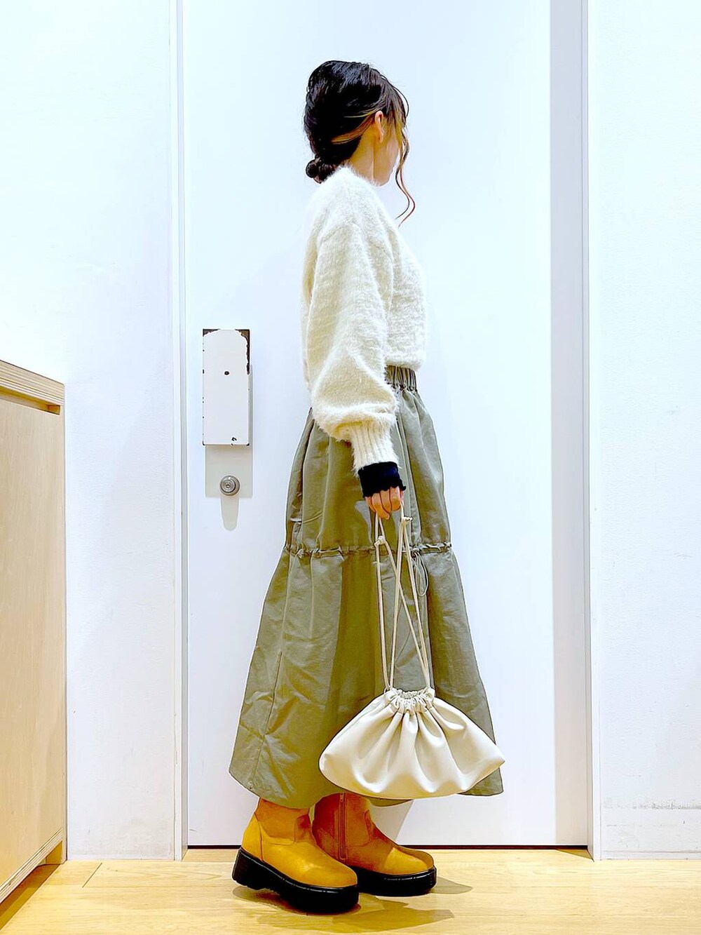 ベージュ系のショルダーバッグ、ベージュ系のブーツ、ベージュ系のニット/セーターを着用したレディースの冬コーディネートの4枚目の写真