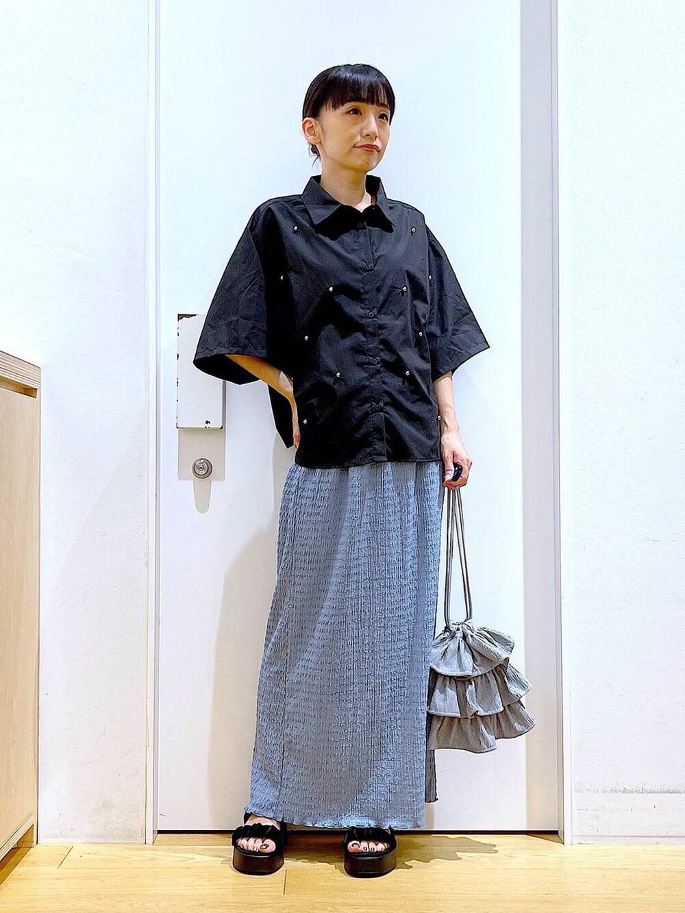 ブラック系のサンダル、ブルー系のスカート、グレー系のショルダーバッグを着用したレディースの秋コーディネートの2枚目の写真