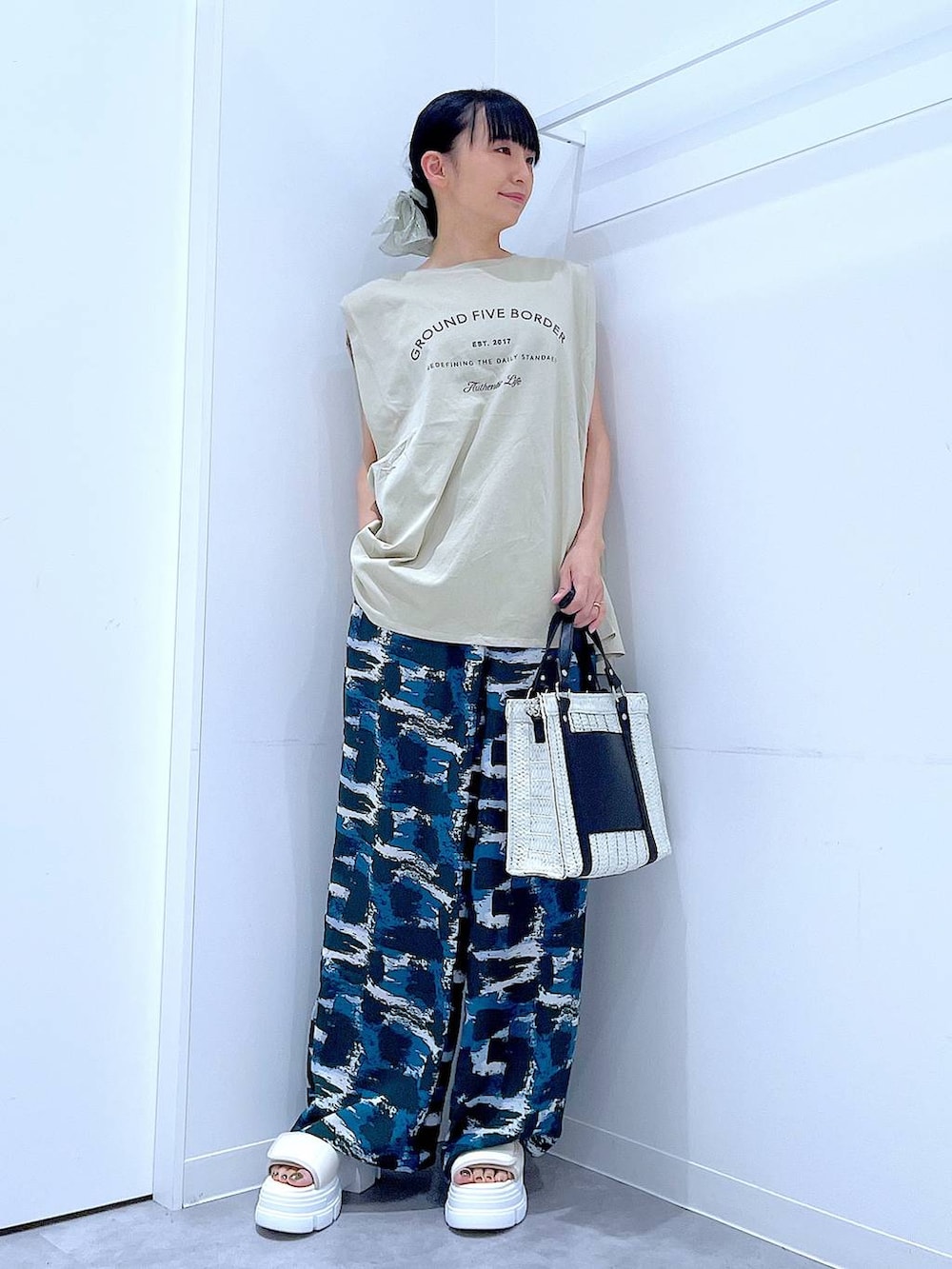 ホワイト系のショルダーバッグ、ホワイト系のサンダル、ベージュ系のTシャツ/カットソーを着用したレディースの夏コーディネートの2枚目の写真