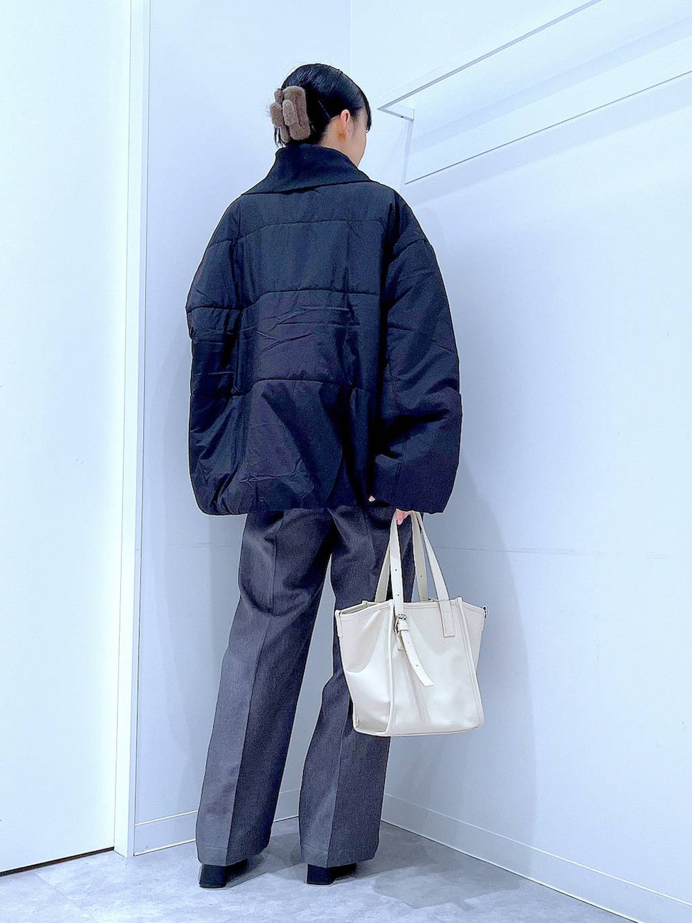 ブラック系のブルゾン、ブラック系のブーツ、グレー系のスラックスを着用したレディースの冬コーディネートの5枚目の写真