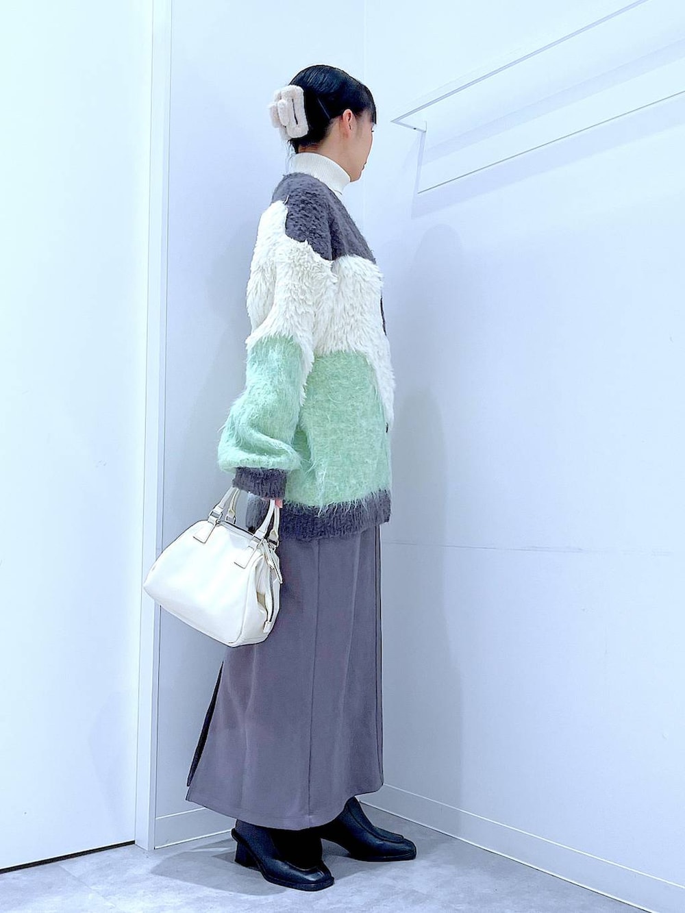 グリーン系のカーディガン/ボレロ、ブラック系のブーツ、ホワイト系のショルダーバッグを着用したレディースの冬コーディネートの4枚目の写真