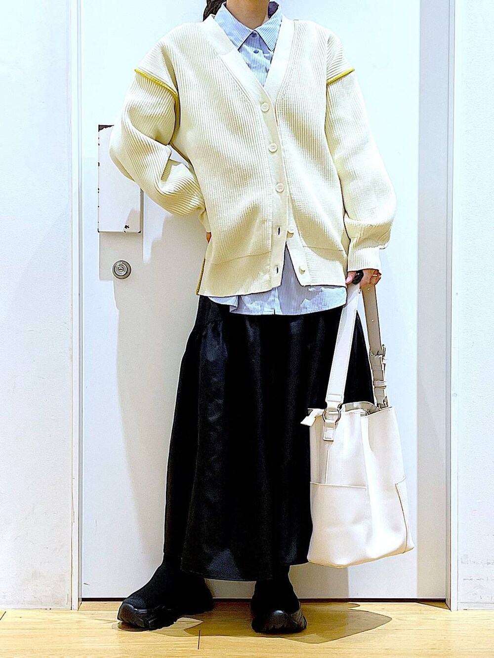 ホワイト系のショルダーバッグ、ホワイト系のカーディガン/ボレロ、ブラック系のスカートを着用したレディースの春コーディネートの6枚目の写真