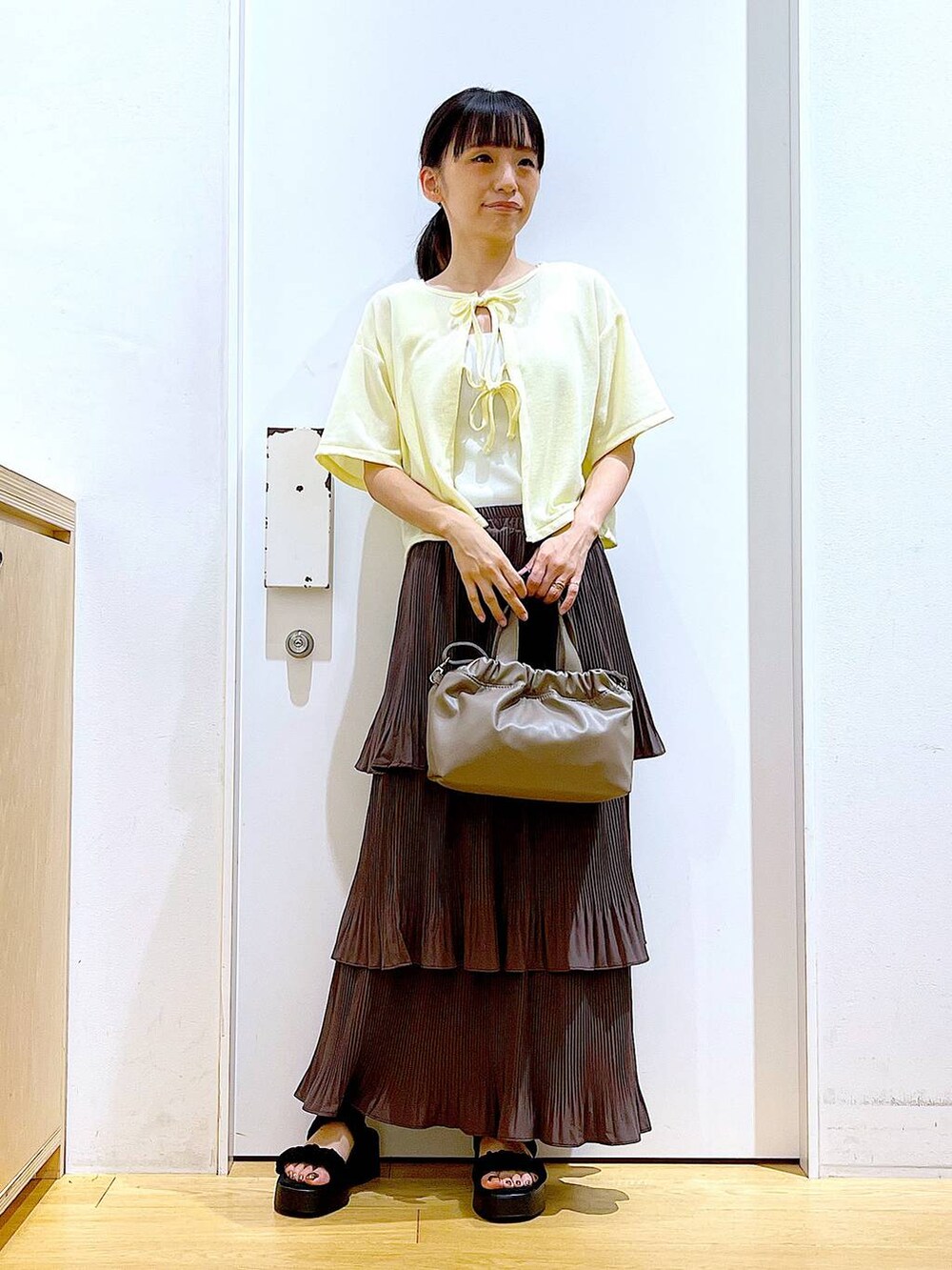 ブラウン系のスカート、ブラウン系のショルダーバッグ、ブラック系のサンダルを着用したレディースの秋コーディネートの2枚目の写真