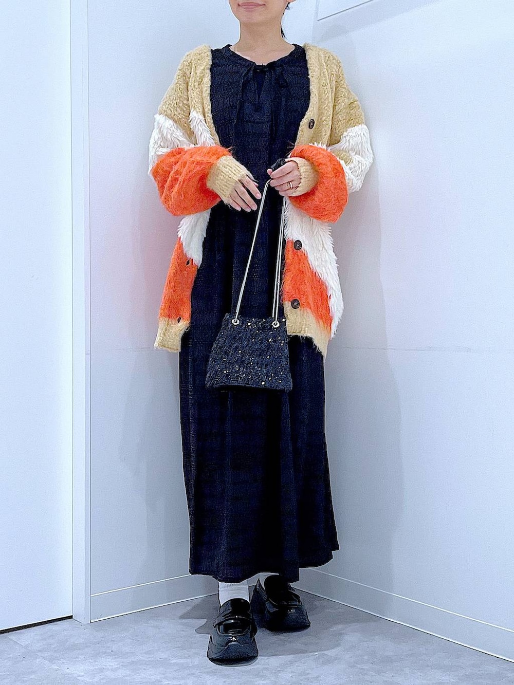 ブラック系のショルダーバッグ、ブラック系のローファー、オレンジ系のカーディガン/ボレロを着用したレディースの秋コーディネートの6枚目の写真