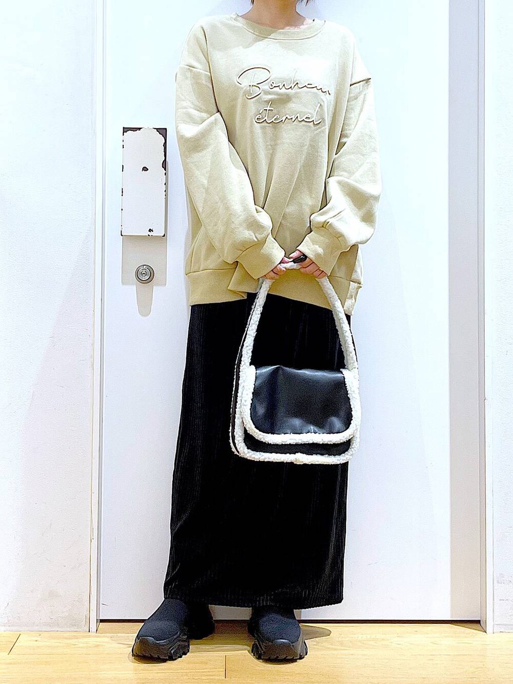 ブラック系のブーツ、ブラック系のショルダーバッグ、ブラック系のスカートを着用したレディースの冬コーディネートの6枚目の写真