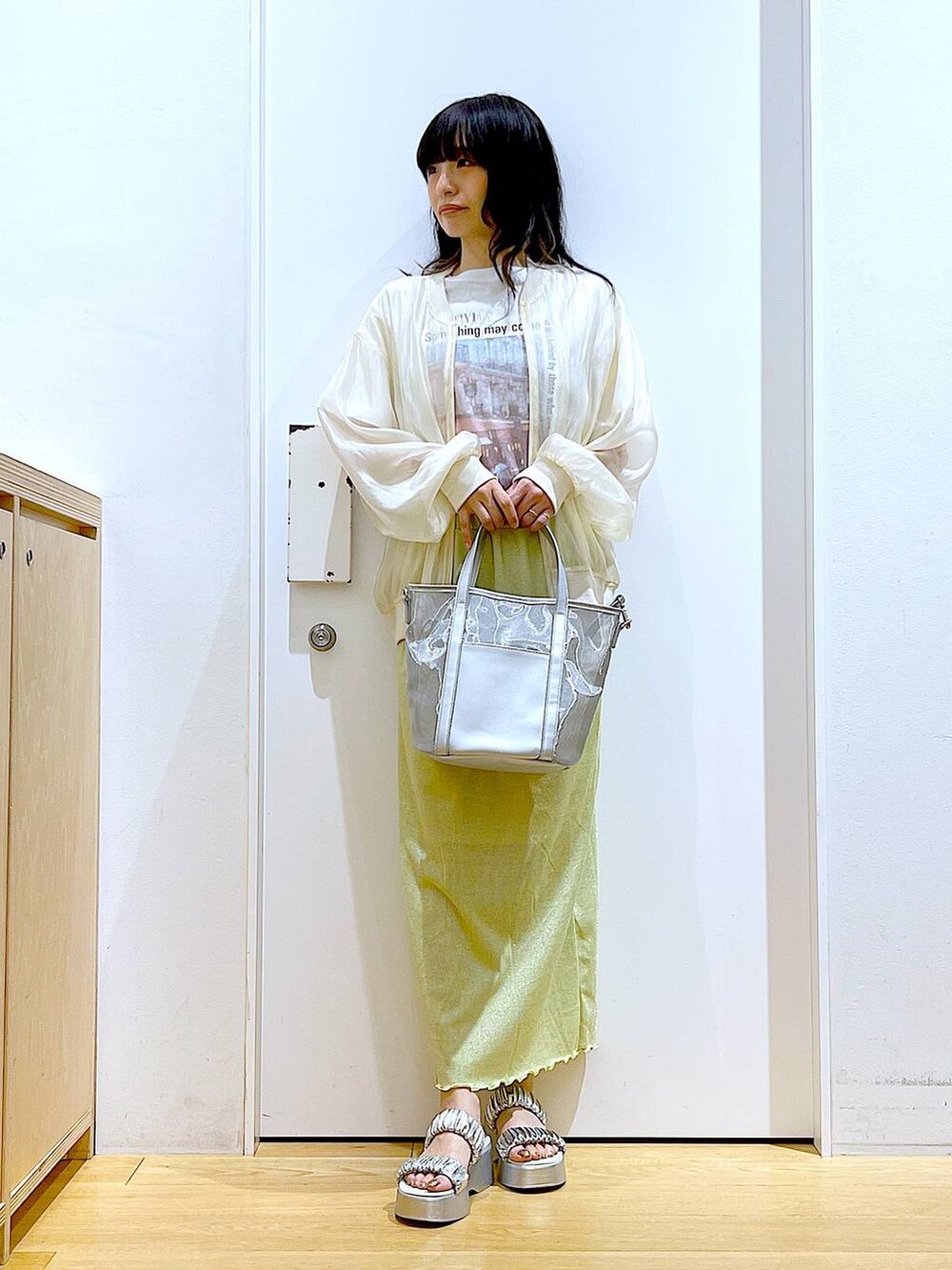 グリーン系のスカート、シルバー系のサンダル、シルバー系のトートバッグを着用したレディースの夏コーディネートの2枚目の写真