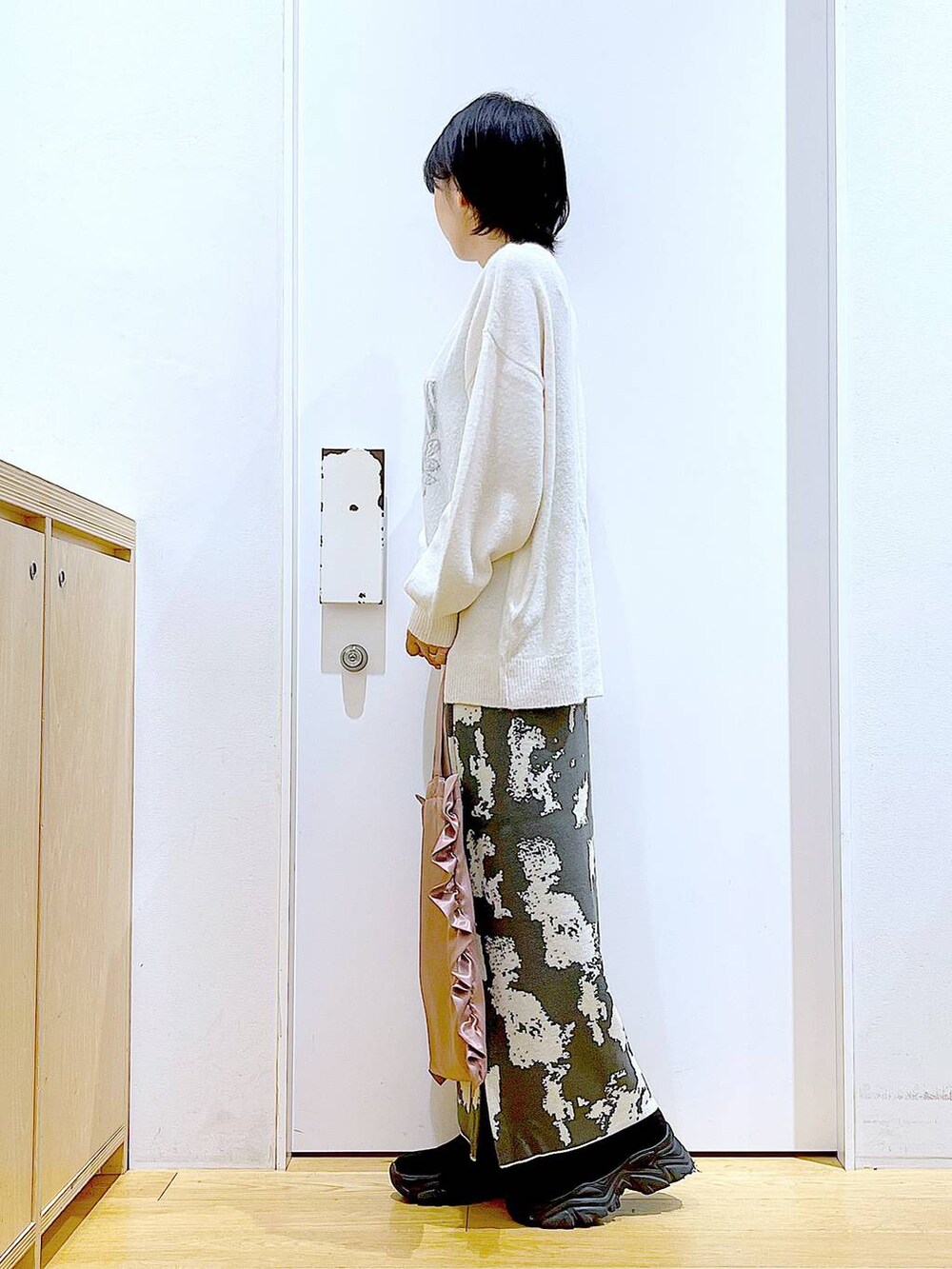 グレー系のスカート、ブラック系のブーツ、ベージュ系のニット/セーターを着用したレディースの秋コーディネートの3枚目の写真