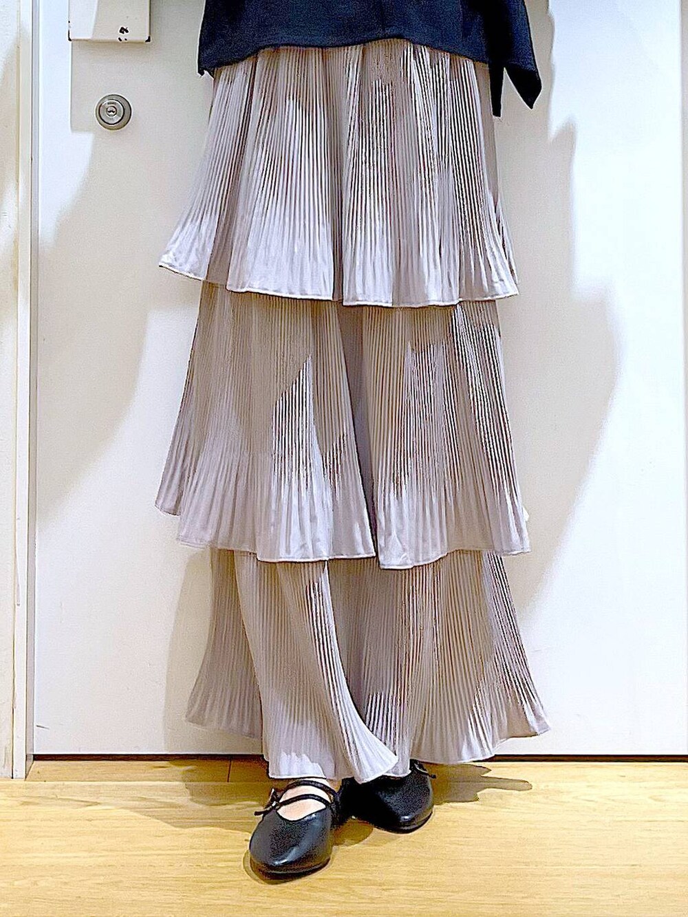 グレー系のスカート、ブラック系のショルダーバッグ、ブラック系のパンプスを着用したレディースの秋コーディネートの8枚目の写真