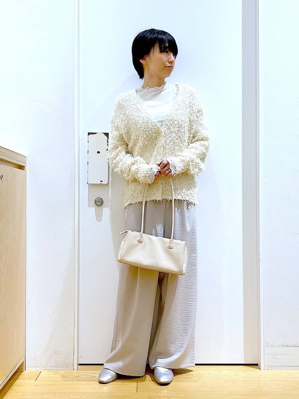 ホワイト系のトートバッグ、ベージュ系のTシャツ/カットソー、シルバー系のパンプスを着用したレディースの冬コーディネートの2枚目の写真