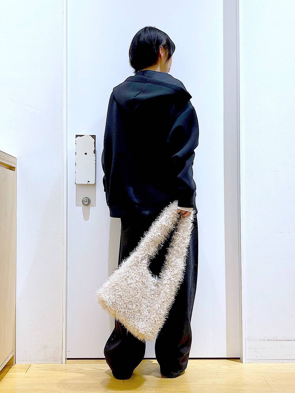 ベージュ系のスリッポン、ベージュ系のショルダーバッグ、ブラック系のデニムパンツを着用したレディースの冬コーディネートの5枚目の写真