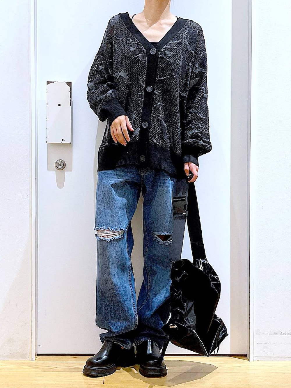ブラック系のサンダル、ブラック系のカーディガン/ボレロ、ブルー系のデニムパンツを着用したレディースの春コーディネートの6枚目の写真