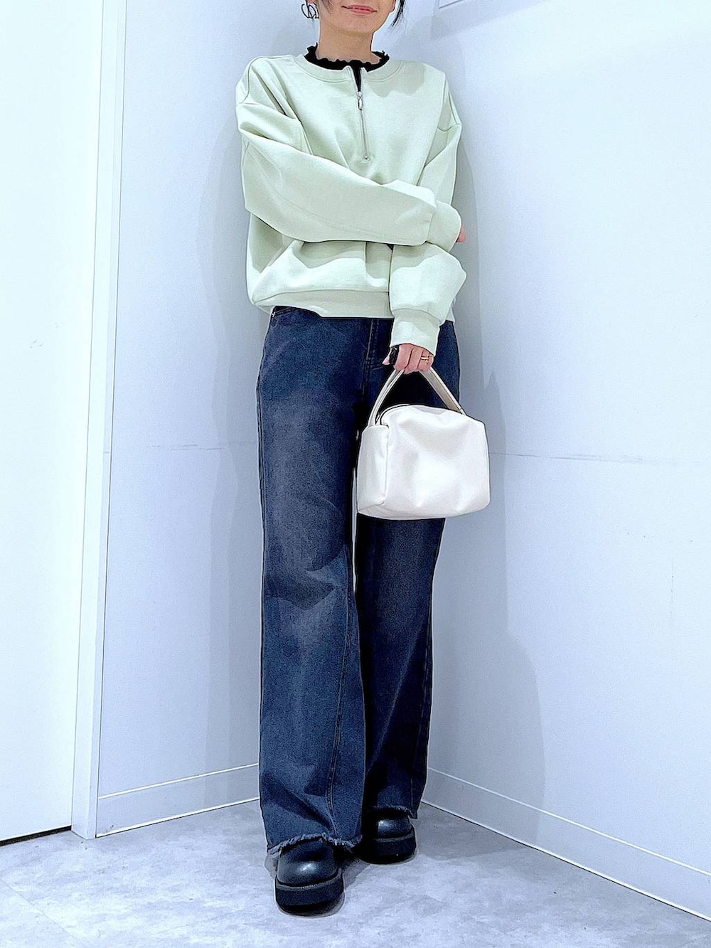 ホワイト系のショルダーバッグ、グリーン系のスウェット、ブラック系のデニムパンツを着用したレディースの春コーディネートの6枚目の写真