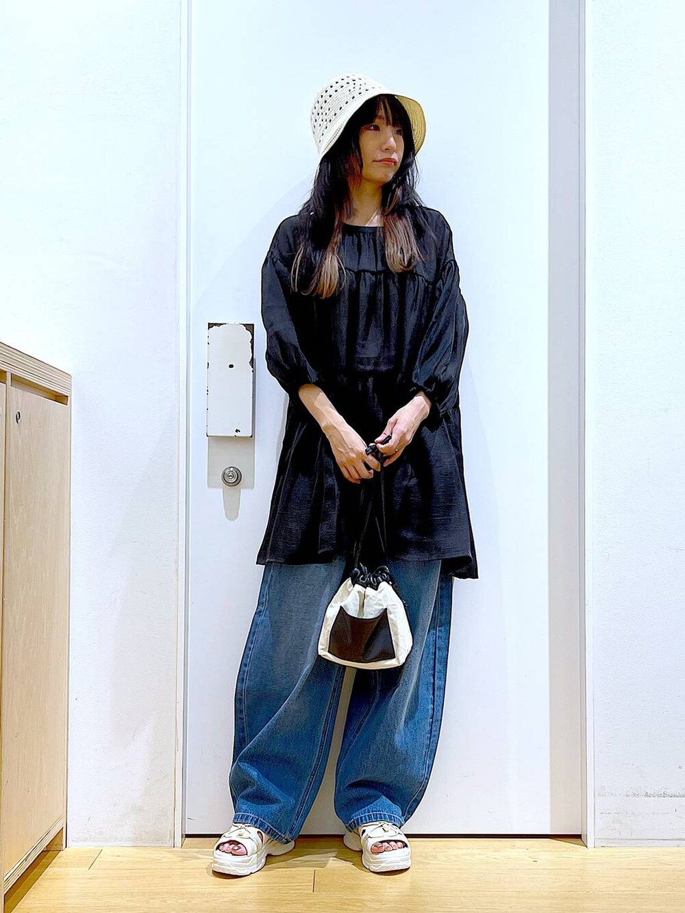 ホワイト系のショルダーバッグ、ブルー系のデニムパンツ、ホワイト系のサンダルを着用したレディースの夏コーディネートの2枚目の写真