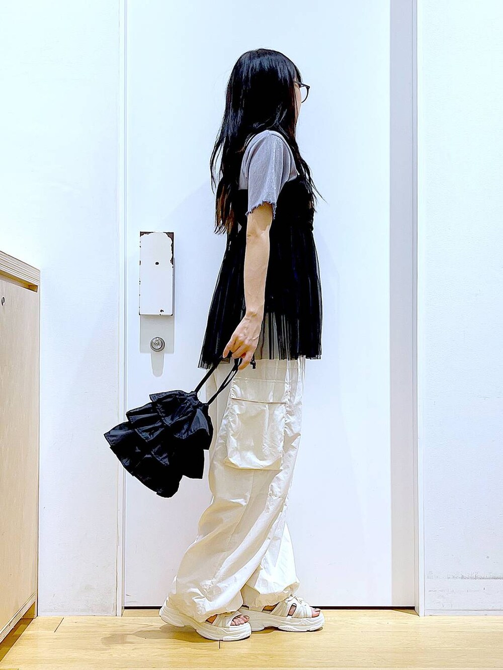 ブラック系のショルダーバッグ、ホワイト系のカーゴパンツ、ブラック系のキャミソールを着用したレディースの夏コーディネートの4枚目の写真