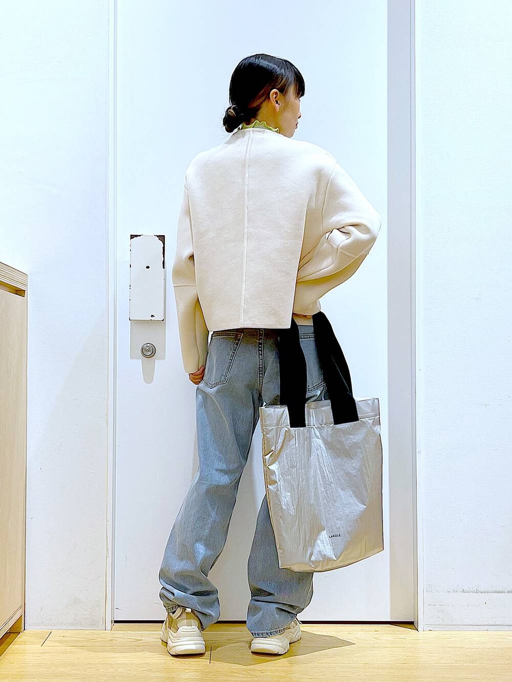 グリーン系のTシャツ/カットソー、ベージュ系のスニーカー、ブルー系のデニムパンツを着用したレディースの冬コーディネートの5枚目の写真