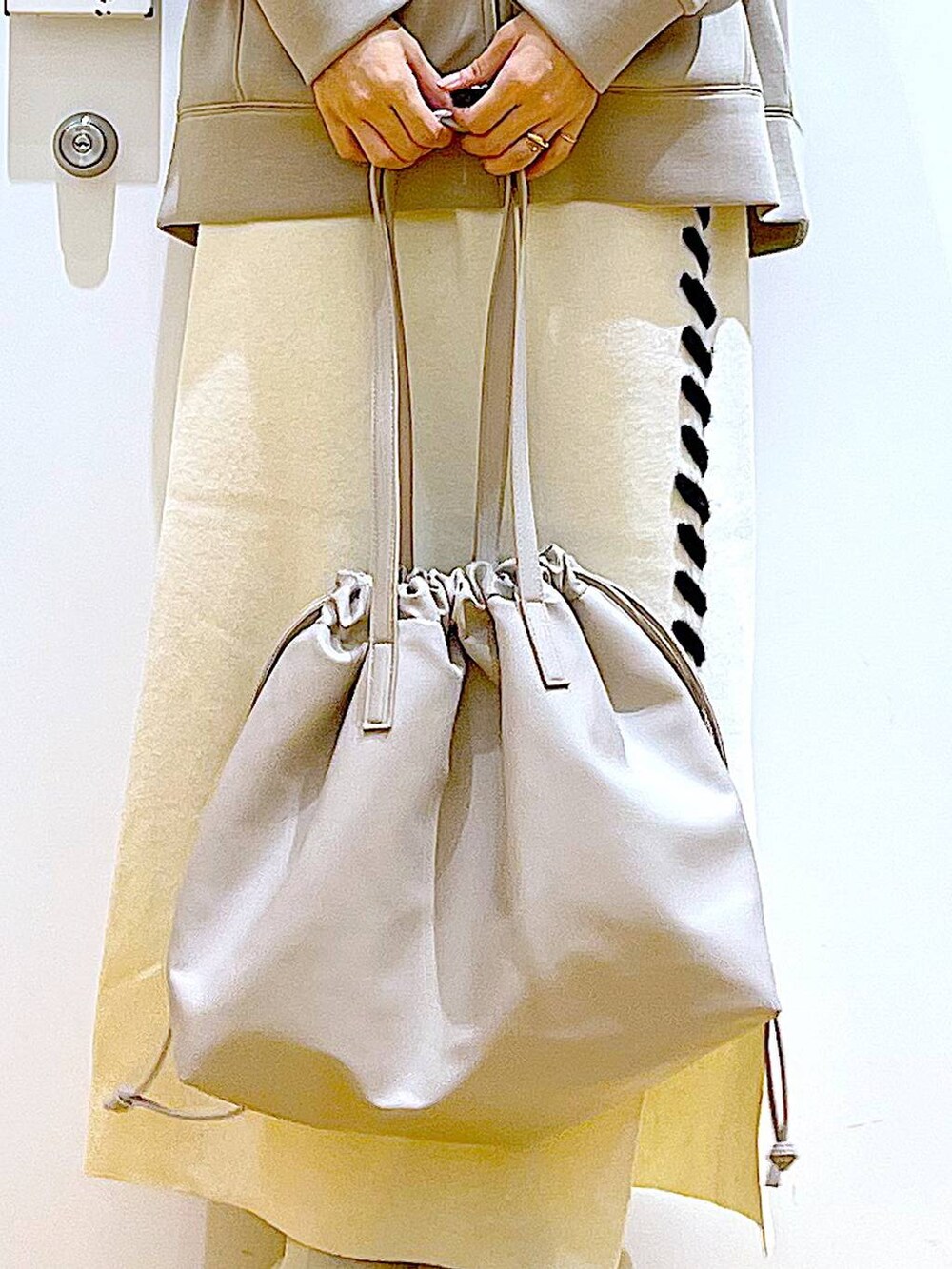 ベージュ系のトートバッグ、ベージュ系のブーツ、ベージュ系のスカートを着用したレディースの秋コーディネートの9枚目の写真