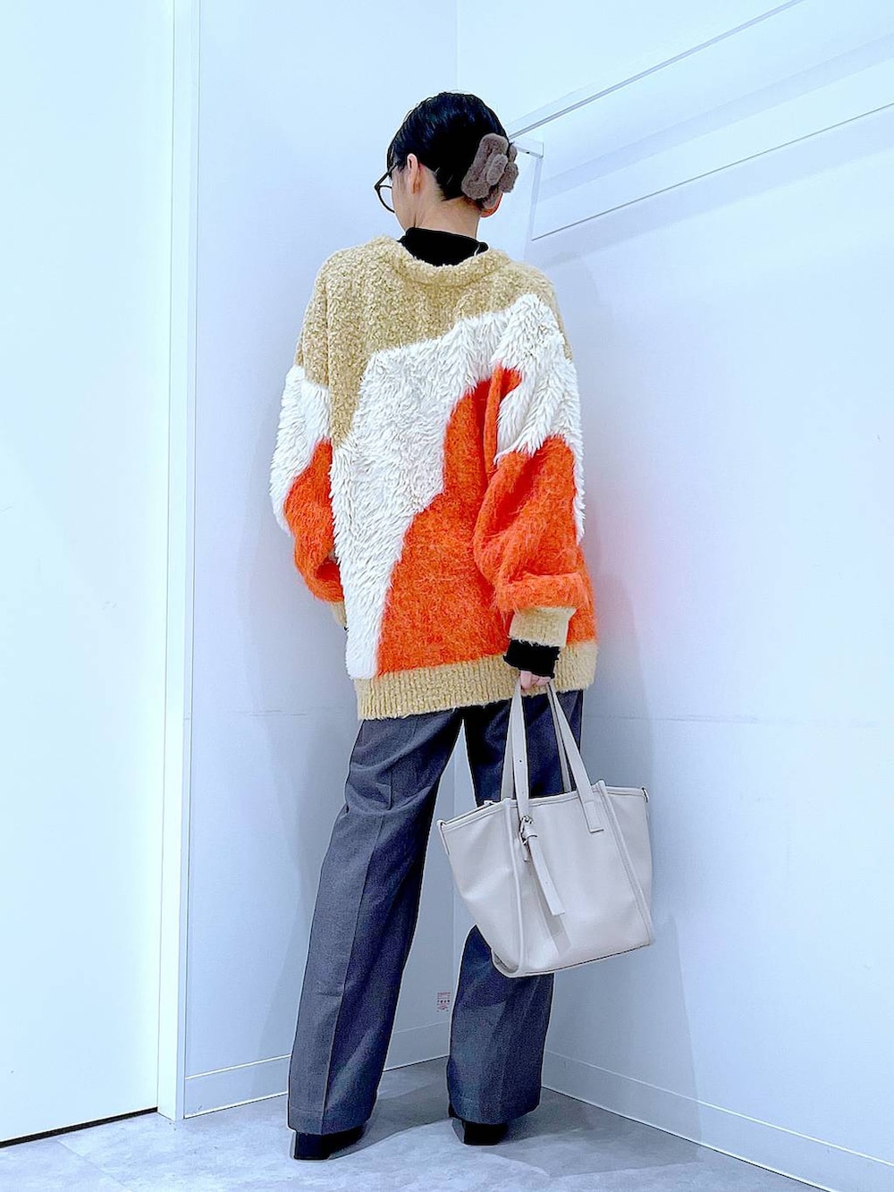 オレンジ系のカーディガン/ボレロ、ブラック系のブーツ、グレー系のスラックスを着用したレディースの冬コーディネートの5枚目の写真