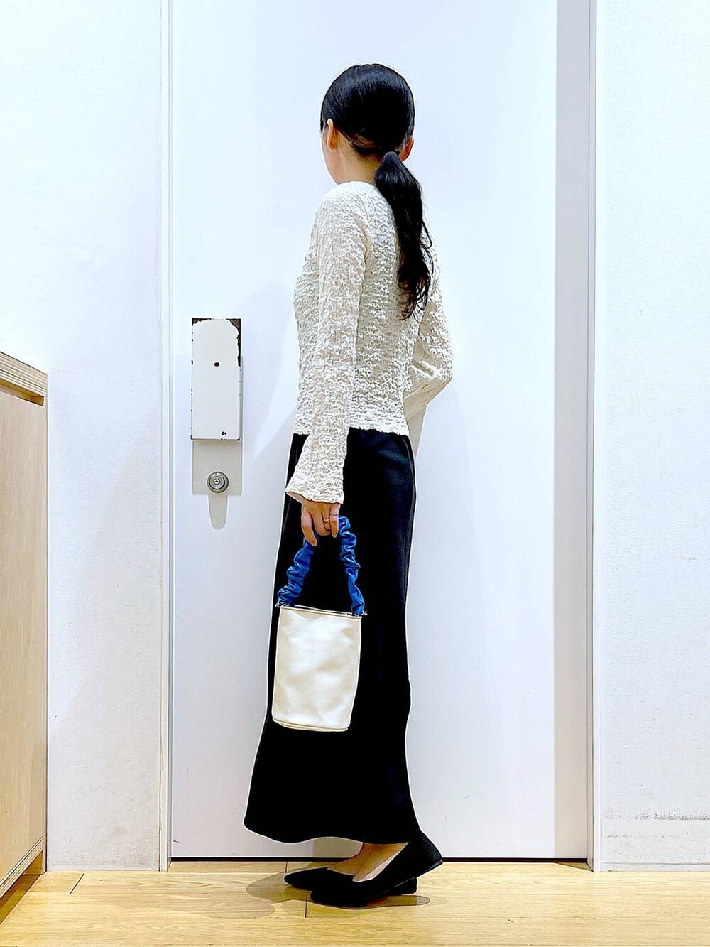 ブルー系のショルダーバッグ、ブラック系のパンプス、ブラック系のワンピースを着用したレディースの春コーディネートの3枚目の写真