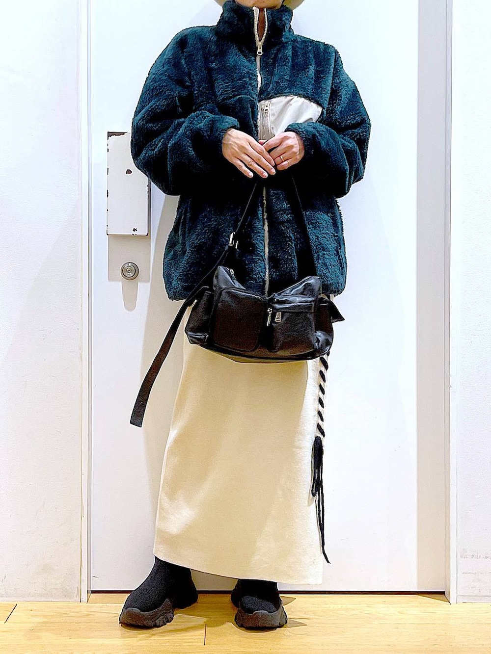 ブラック系のブーツ、ベージュ系のスカート、ブラック系のショルダーバッグを着用したレディースの冬コーディネートの6枚目の写真