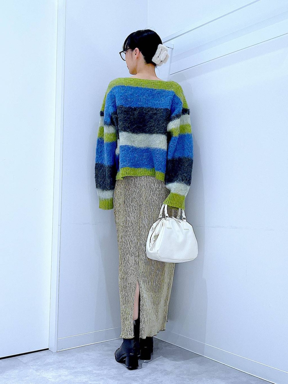 ブラック系のブーツ、ホワイト系のショルダーバッグ、ブルー系のニット/セーターを着用したレディースの冬コーディネートの5枚目の写真