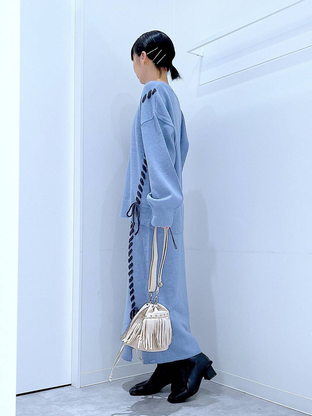 ブルー系のニット/セーター、ブルー系のスカート、ブラック系のブーツを着用したレディースの秋コーディネートの3枚目の写真