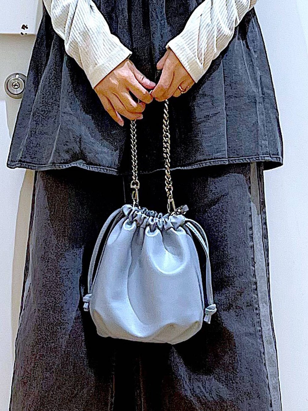 ブルー系のショルダーバッグ、ホワイト系のパンプス、ブラック系のデニムスカートを着用したレディースの春コーディネートの9枚目の写真