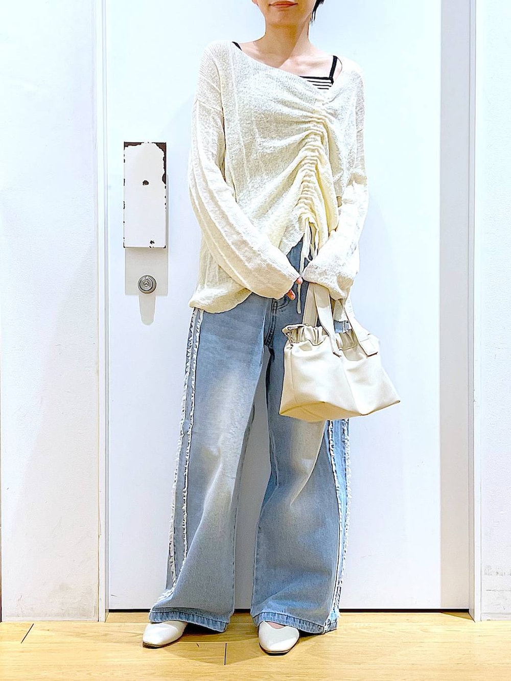 ホワイト系のショルダーバッグ、ホワイト系のパンプス、ブルー系のデニムパンツを着用したレディースの春コーディネートの6枚目の写真