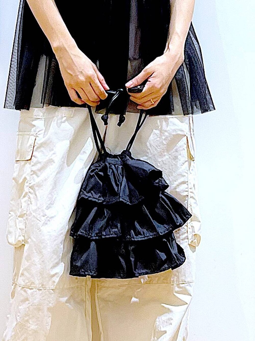 ブラック系のショルダーバッグ、ホワイト系のカーゴパンツ、ブラック系のキャミソールを着用したレディースの夏コーディネートの9枚目の写真