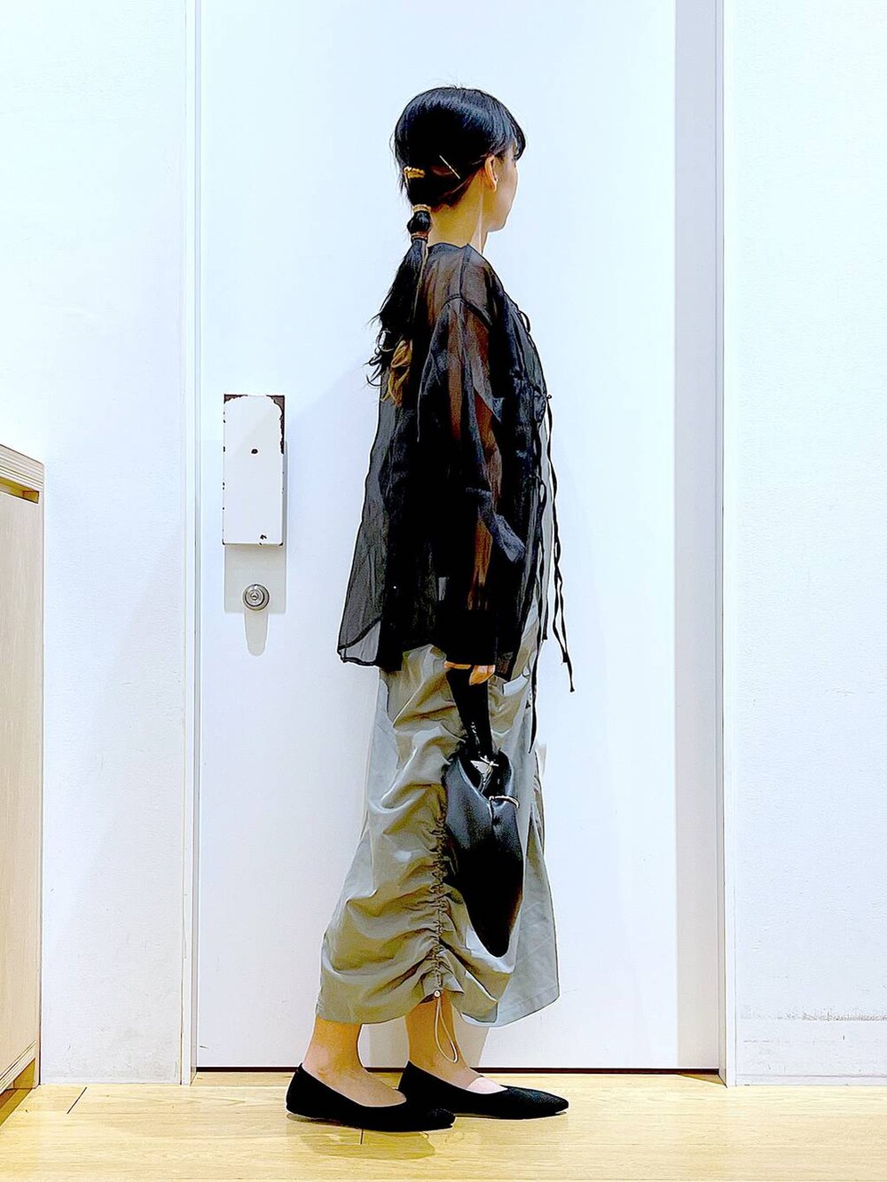 ブラック系のショルダーバッグ、ブラック系のパンプス、グリーン系のワンピースを着用したレディースの春コーディネートの4枚目の写真