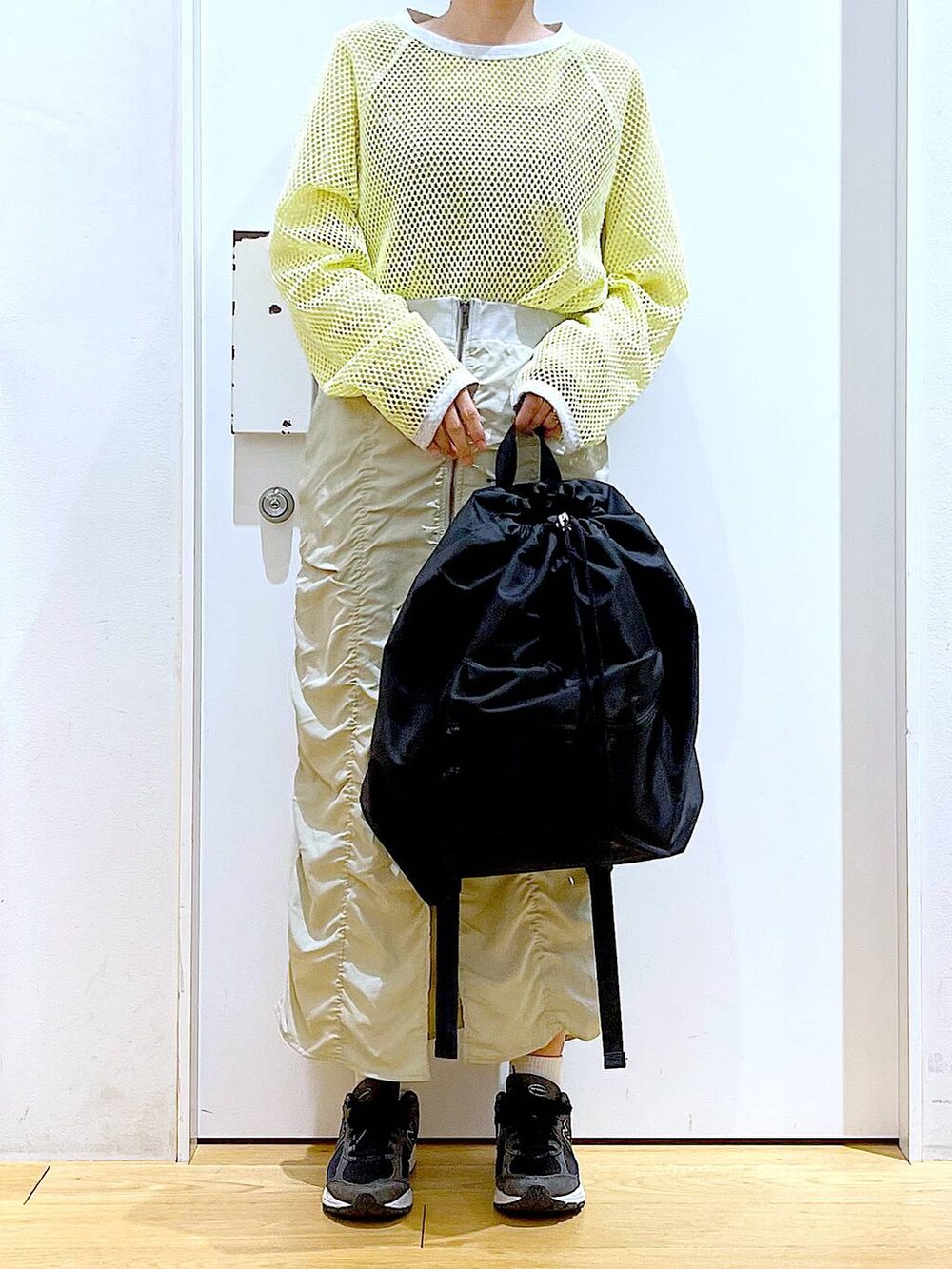 ベージュ系のスカート、ブラック系のバックパック/リュック、イエロー系のTシャツ/カットソーを着用したレディースの春コーディネートの6枚目の写真