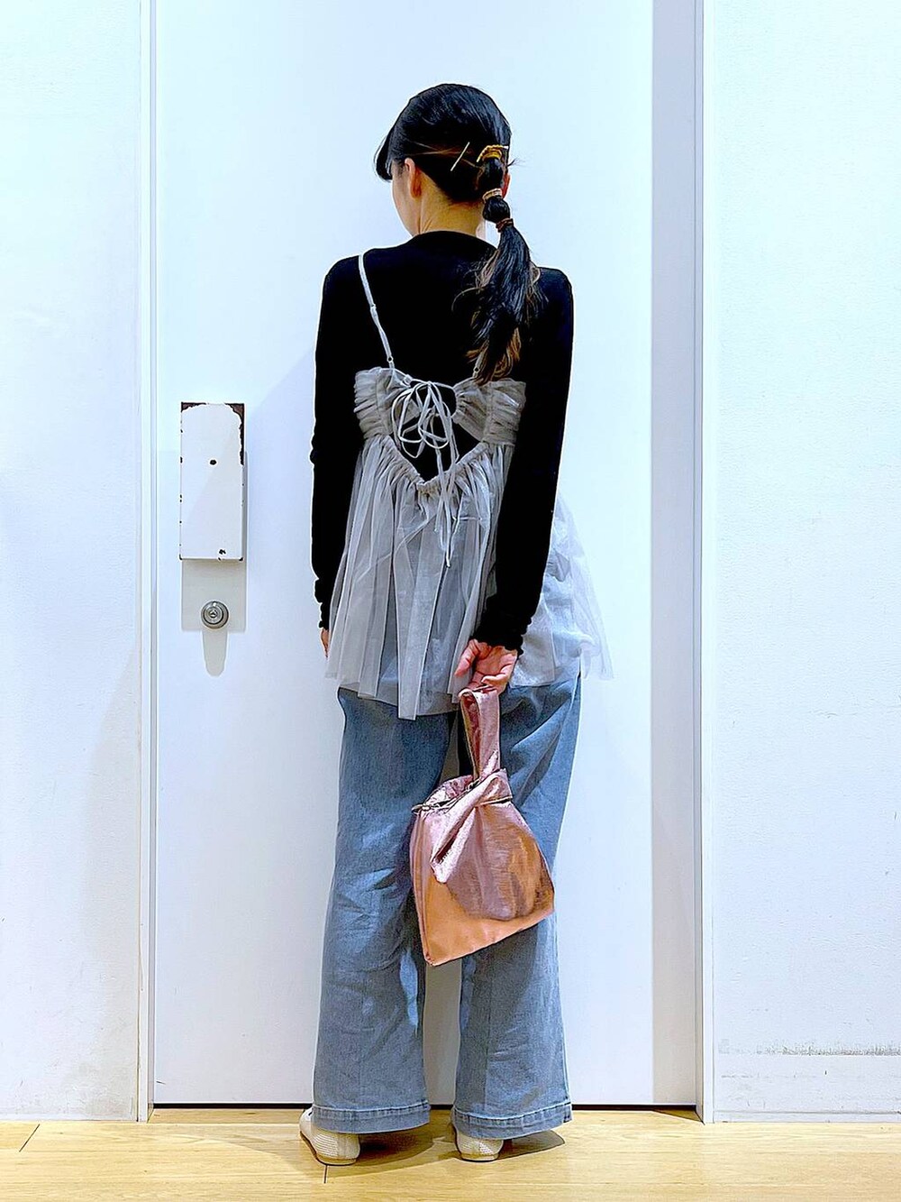 ブルー系のデニムパンツ、ピンク系のショルダーバッグ、ホワイト系のパンプスを着用したレディースの春コーディネートの5枚目の写真