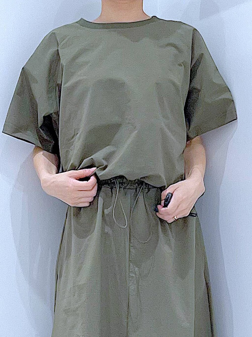 ブラック系のショルダーバッグ、シルバー系のサンダル、グリーン系のTシャツ/カットソーを着用したレディースの夏コーディネートの7枚目の写真