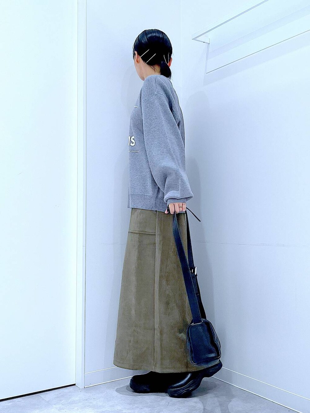 ブラック系のショルダーバッグ、ブラック系のブーツ、グリーン系のスカートを着用したレディースの冬コーディネートの3枚目の写真