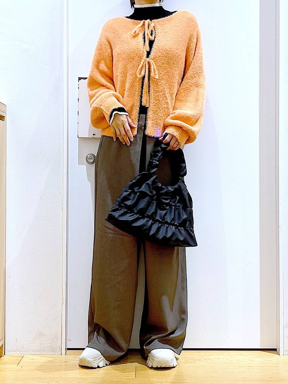 ブラック系のニット/セーター、ベージュ系のブーツ、ブラック系のショルダーバッグを着用したレディースの冬コーディネートの6枚目の写真