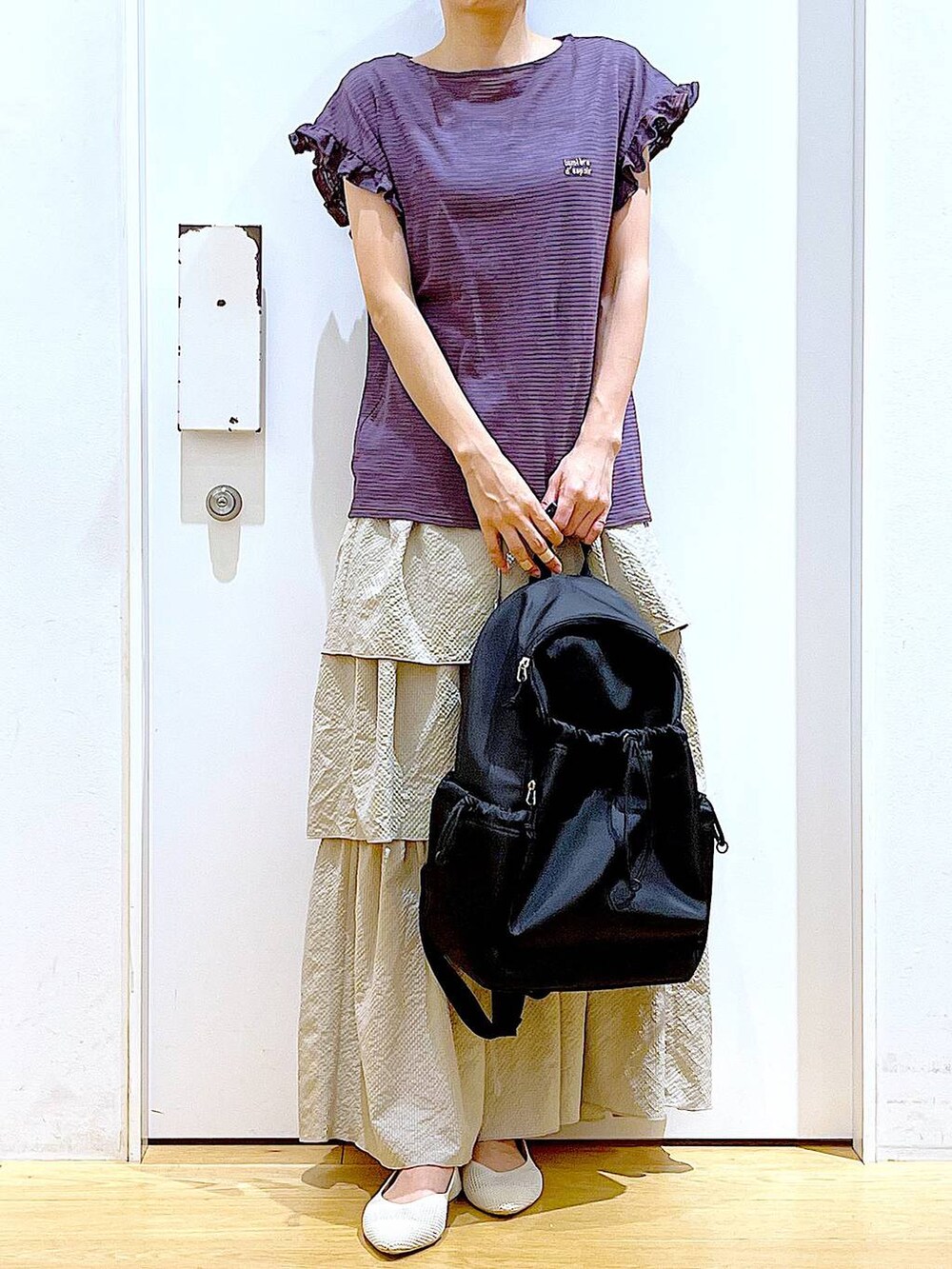 ブラウン系のTシャツ/カットソー、ベージュ系のスカート、ブラック系のバックパック/リュックを着用したレディースの春コーディネートの6枚目の写真