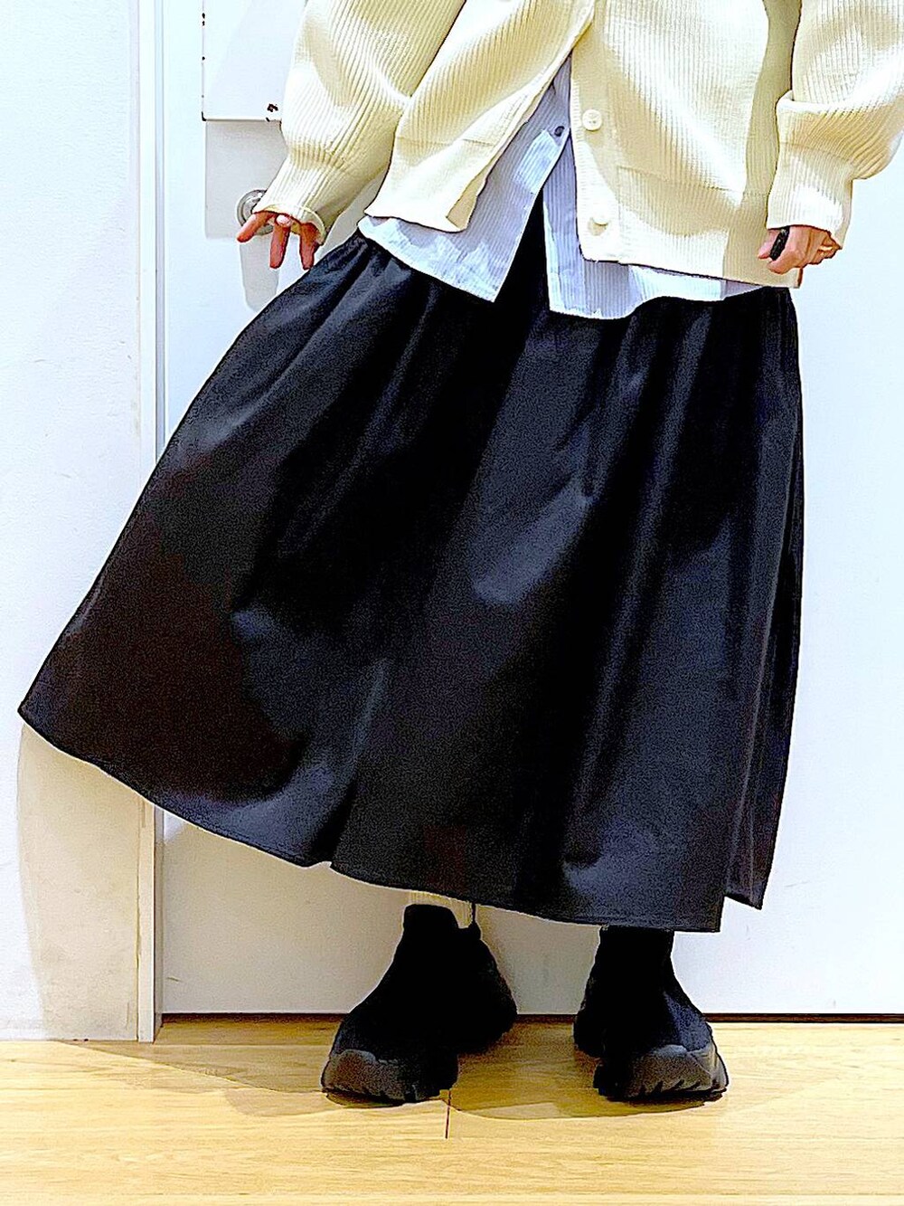 ホワイト系のショルダーバッグ、ホワイト系のカーディガン/ボレロ、ブラック系のスカートを着用したレディースの春コーディネートの8枚目の写真