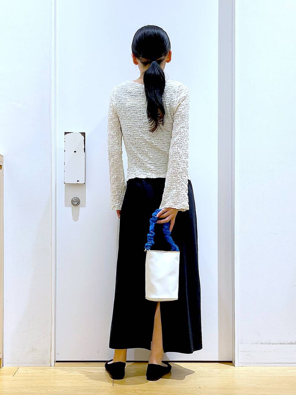 ブルー系のショルダーバッグ、ブラック系のパンプス、ブラック系のワンピースを着用したレディースの春コーディネートの5枚目の写真