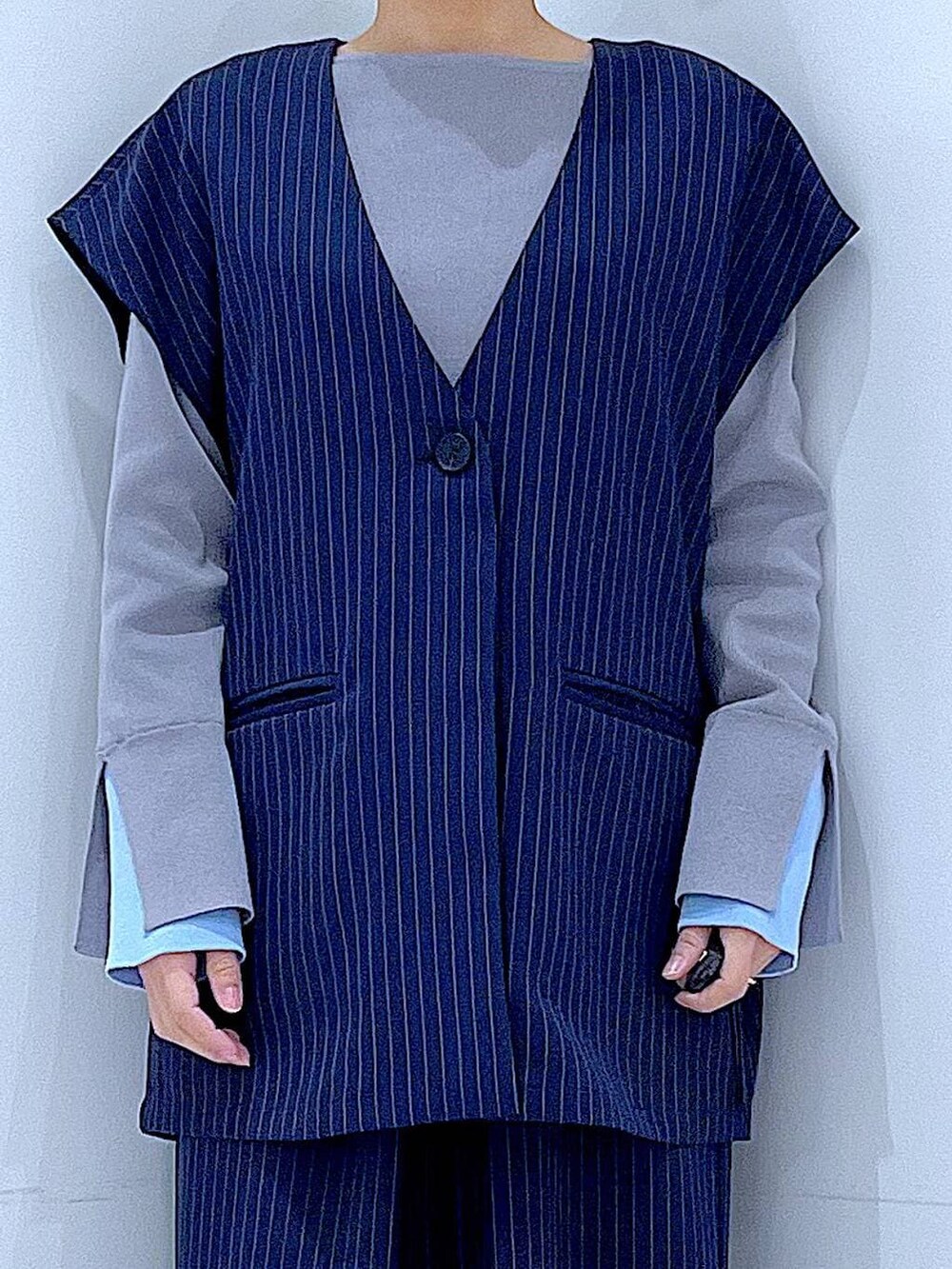 ホワイト系のショルダーバッグ、ブルー系のスラックス、ブルー系のベストを着用したレディースの冬コーディネートの7枚目の写真