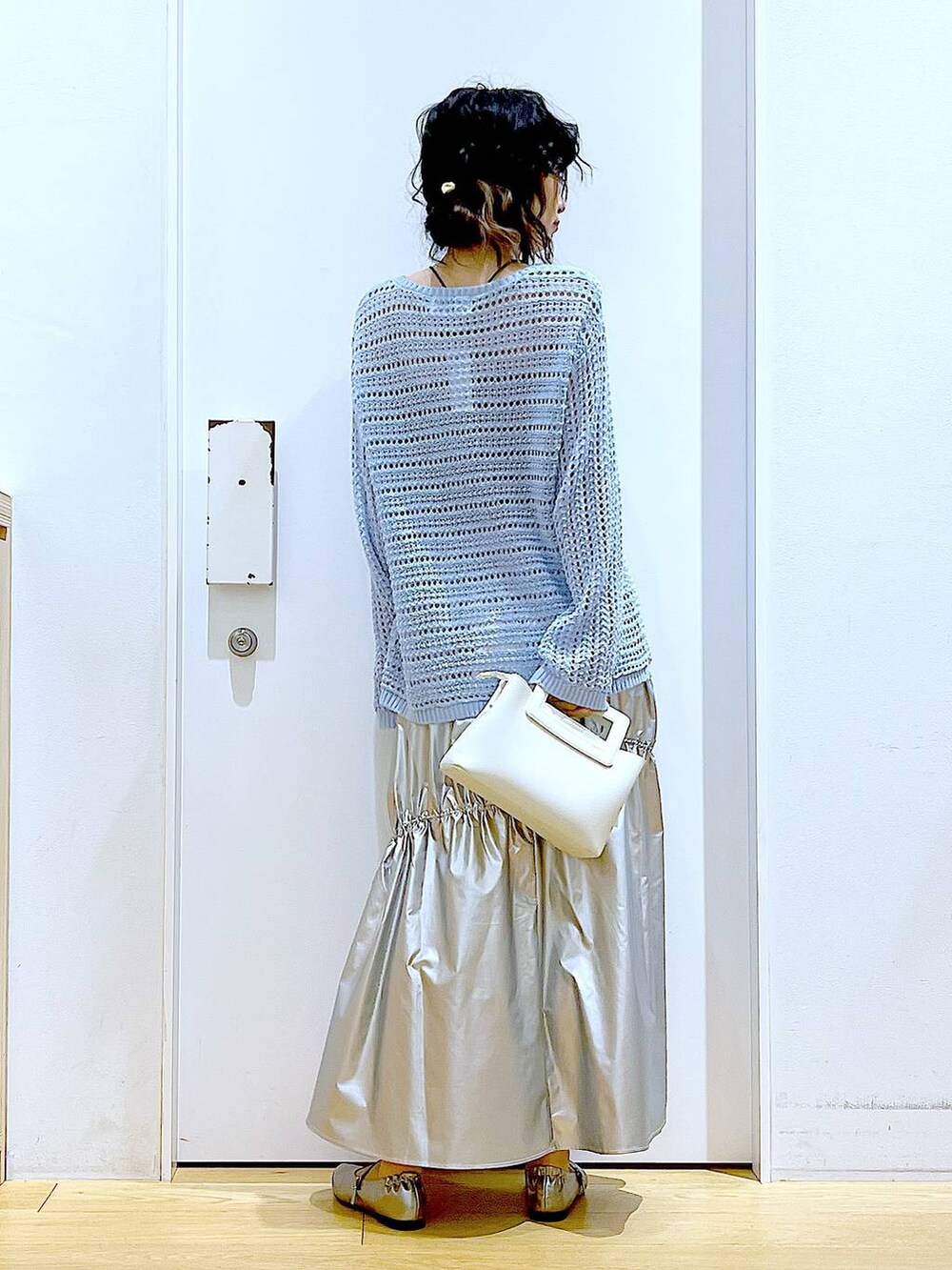 ブルー系のニット/セーター、シルバー系のスカート、ホワイト系のショルダーバッグを着用したレディースの春コーディネートの5枚目の写真