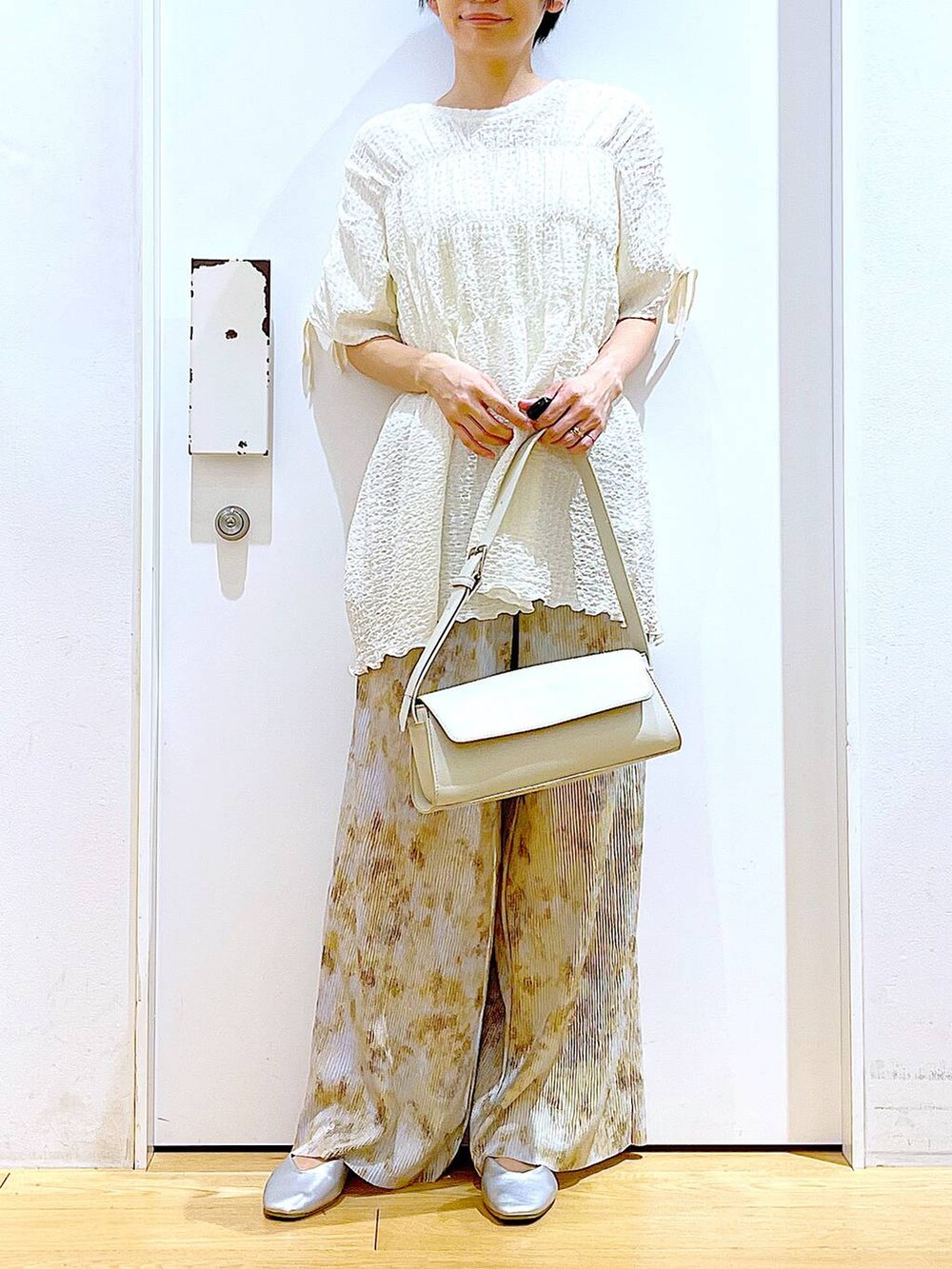 シルバー系のパンプス、ホワイト系のショルダーバッグ、ベージュ系のその他パンツを着用したレディースの春コーディネートの6枚目の写真
